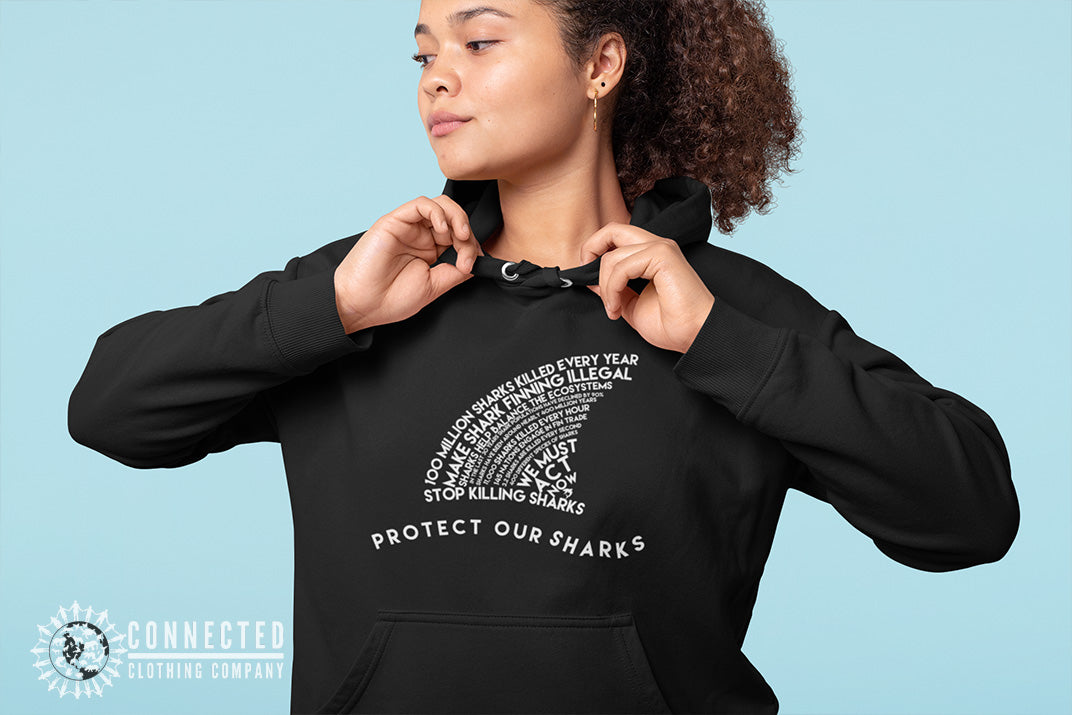 Model wearing black Protect Our Sharks Unisex Hoodie in front of blue backdrop - sweetsherriloudesigns - Ethically and Sustainably Made - 10% donated to Oceana shark conservation