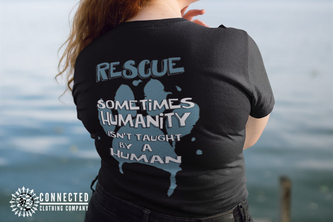 Model wearing Black Show Humanity Tee at the lake that reads "Rescue. Sometimes humanity isn't taught by a human" - sweetsherriloudesigns - Ethically and Sustainably Made - 10% donated to the Society for the Prevention of Cruelty to Animals